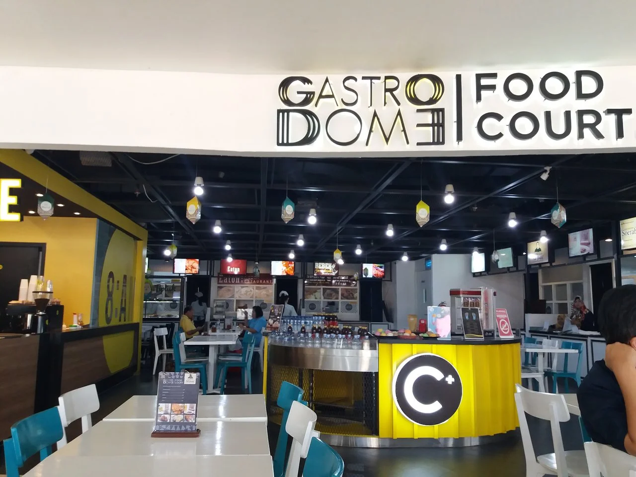 Area food court Gastro Dome di Bandara Juanda dengan meja makan dan konter minuman