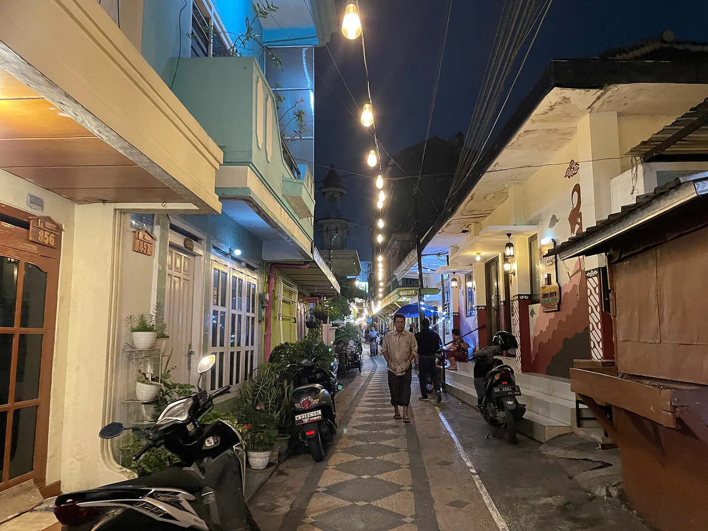 Gang Kampung Kayutangan pada malam hari dengan lampu gantung berjajar dan lantai tegel