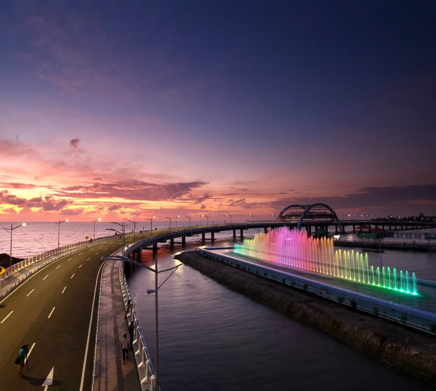 Langit senja jingga di atas Jembatan Suroboyo dan air mancur warna-warni di pesisir Kenjeran, Surabaya