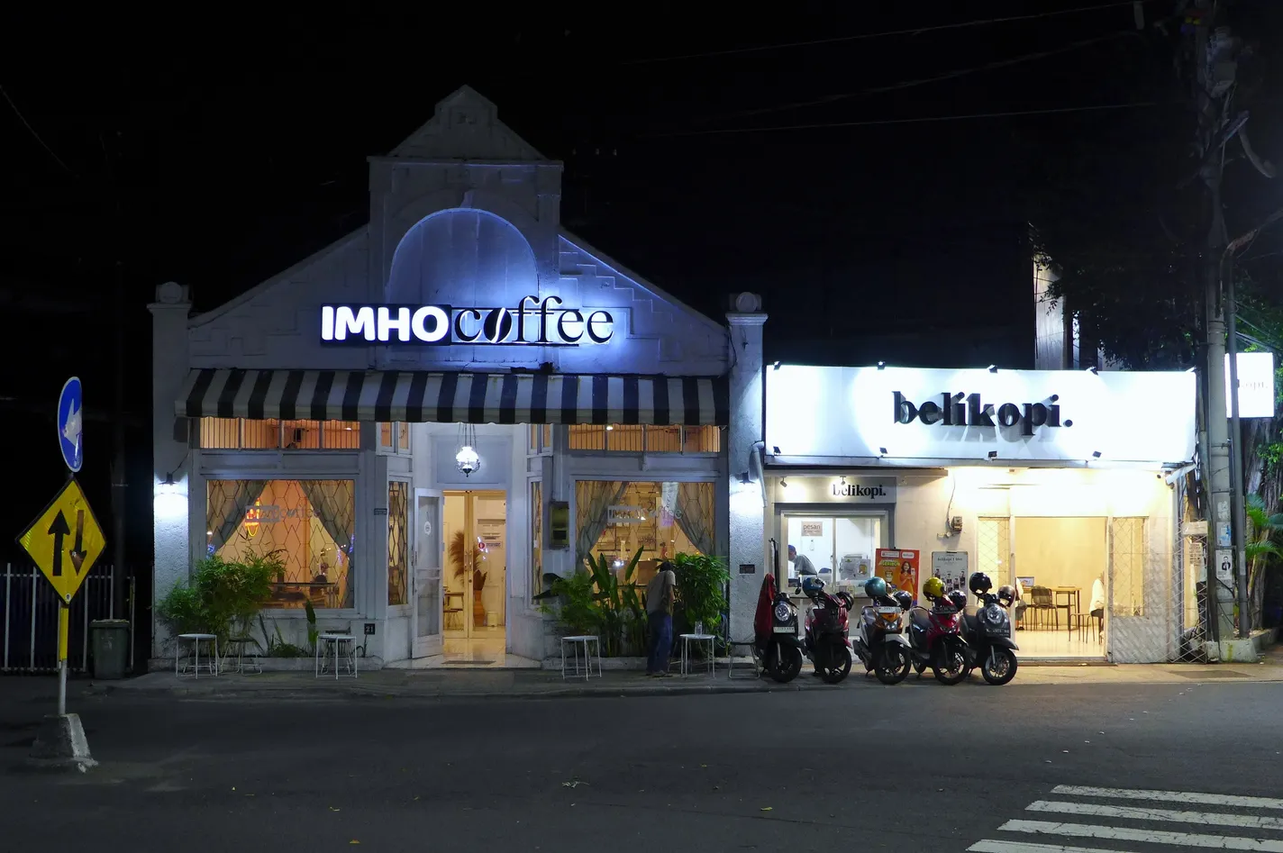 Fasad IMHO Coffee dan belikopi yang terang di sebuah jalan Surabaya pada malam hari